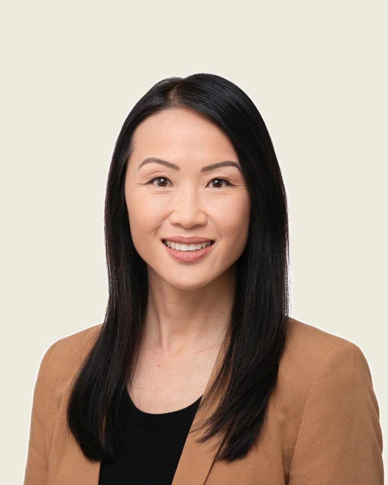 Denise Lee, smiling, in a camel blazer